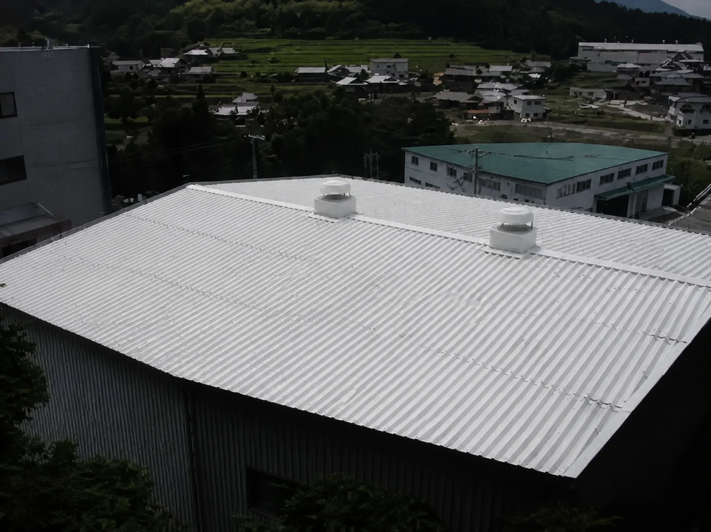 折板屋根・遮熱塗料＋光触媒 施工直後（視認性向上のため手前の樹木を画像処理）